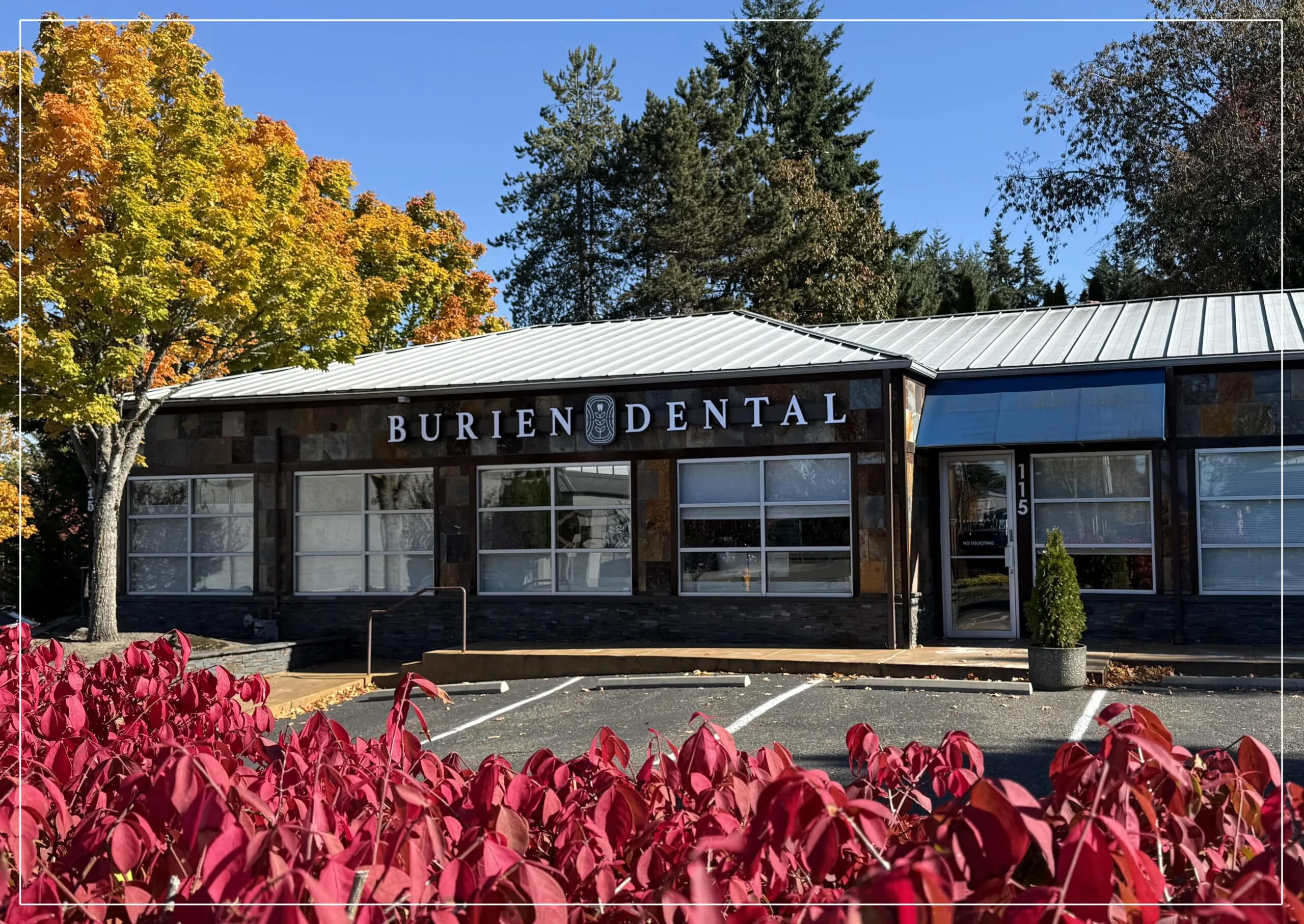 Exterior of Burien Dental showing the main entrance, signage, and surrounding landscaping on a clear day.
